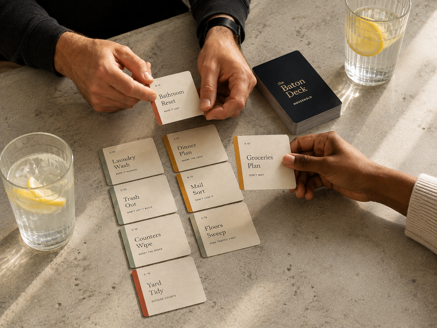 The Baton Deck cards arranged on a table with two people dealing responsibilities